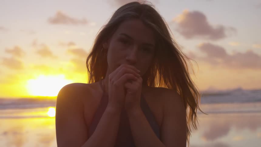 Woman on a beach stares into the camera