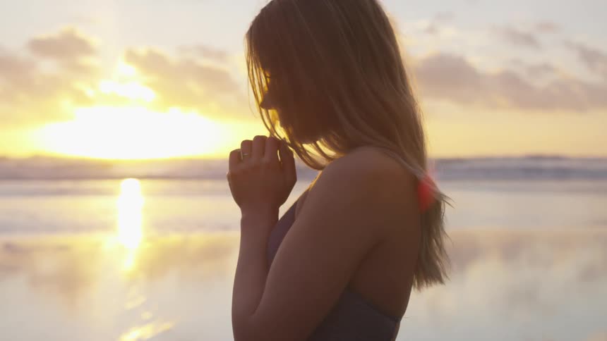 A woman standing with the sun and clouds in the background