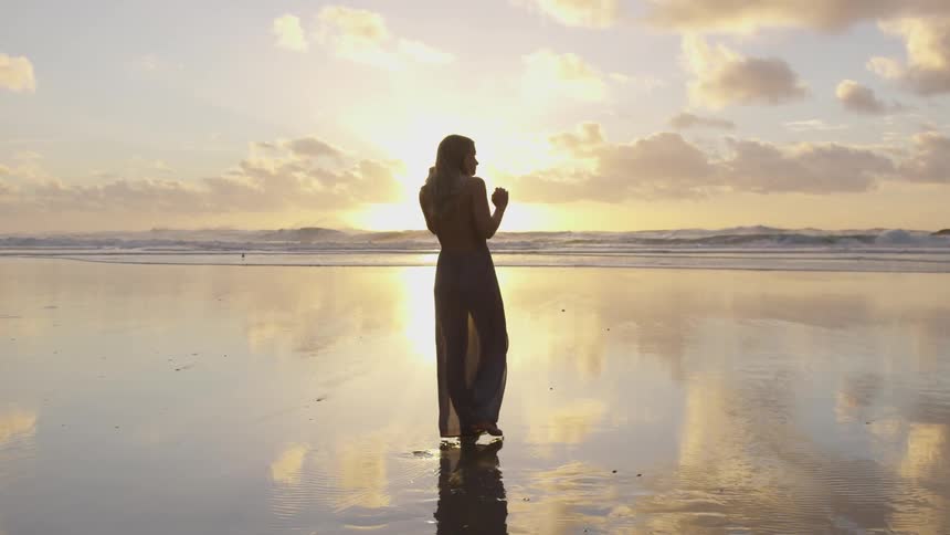 A blonde haired female walking along the beach