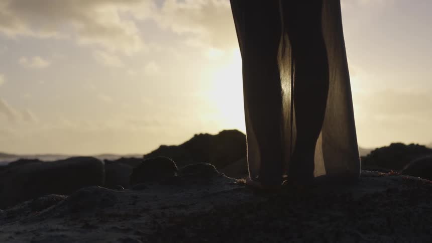 Woman's legs standing on a rock overlooking the ocean