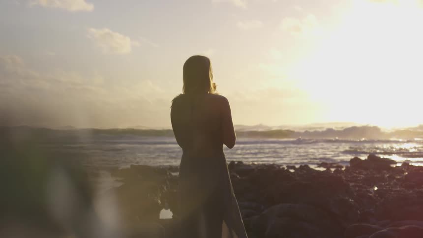 A woman standing in rocks at the edge of the coast