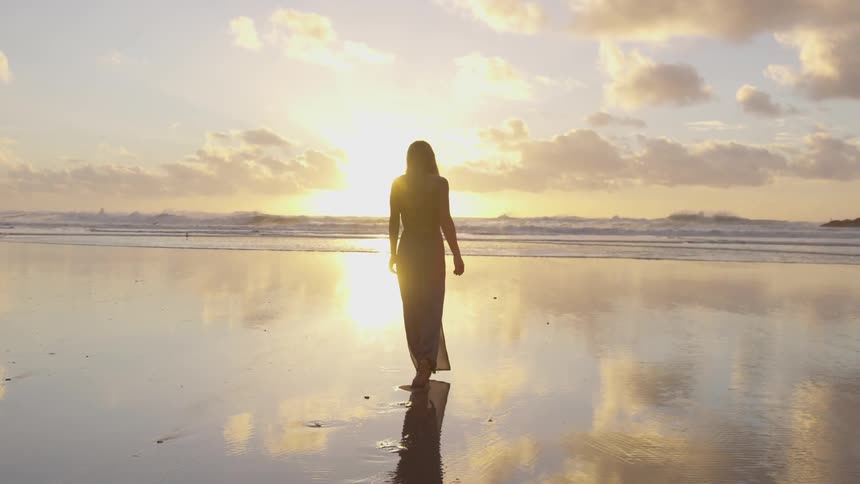 White woman walking towards the sea at the beach