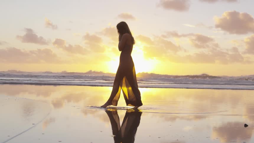Woman walks on the wet sand near the ocean