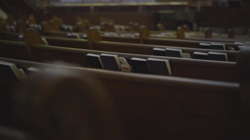 Camera looks over church pews