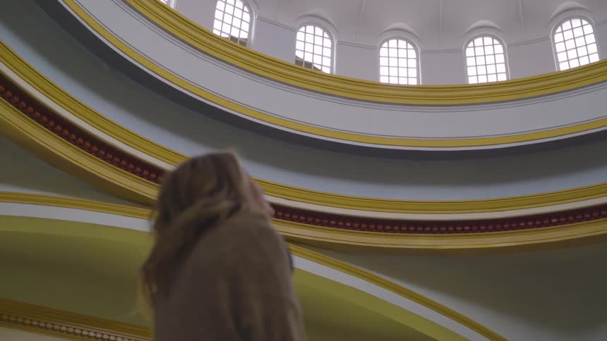 Woman looks up towards the top of the inside of a small building