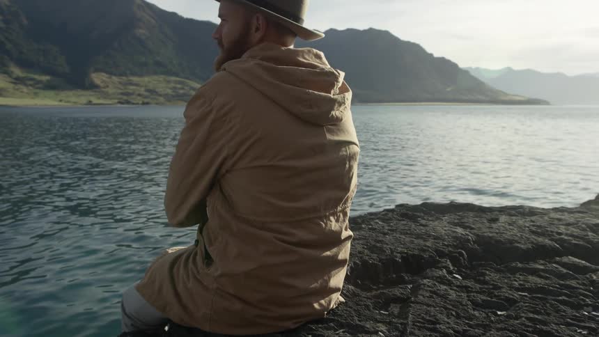 Man sits on a rock overlooking a river