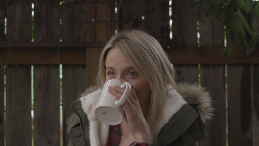 A woman sitting outside drinking from a coffee mug