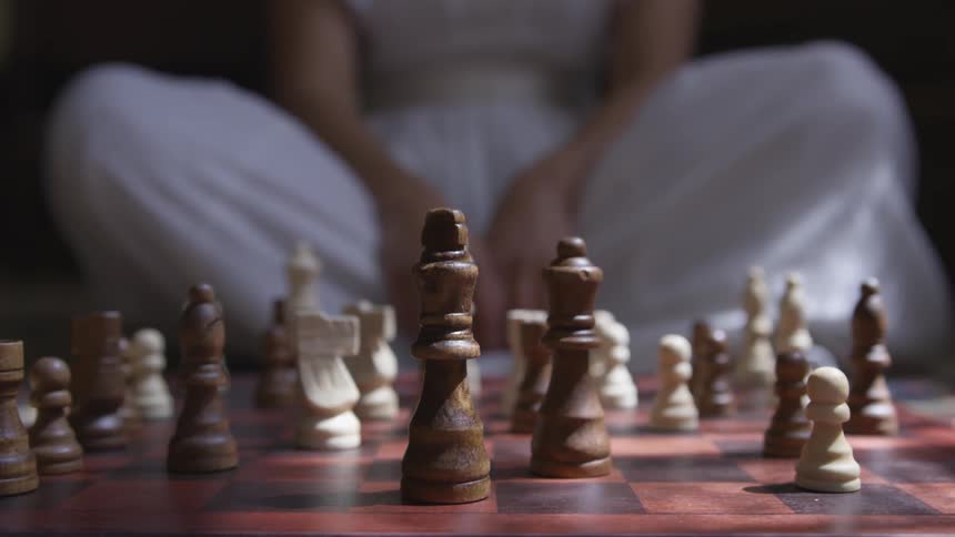 Woman sitting across a chess table with brown and white pieces