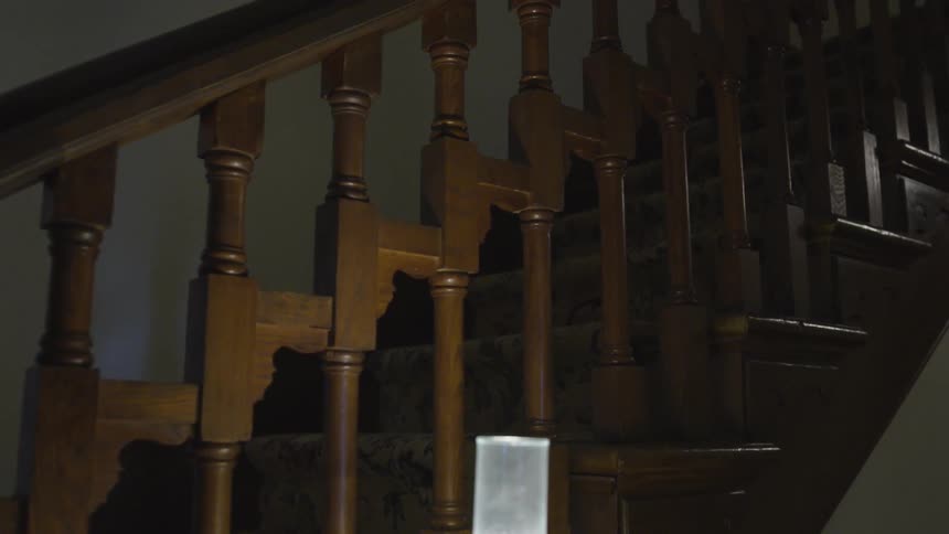 Lit lamp on table next to carpeted staircase