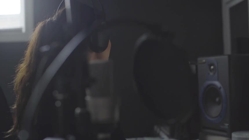 Dj wearing headphones and adjusting equipment in booth