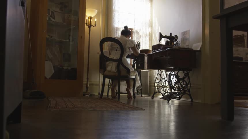A woman is sitting and working with a sewing machine