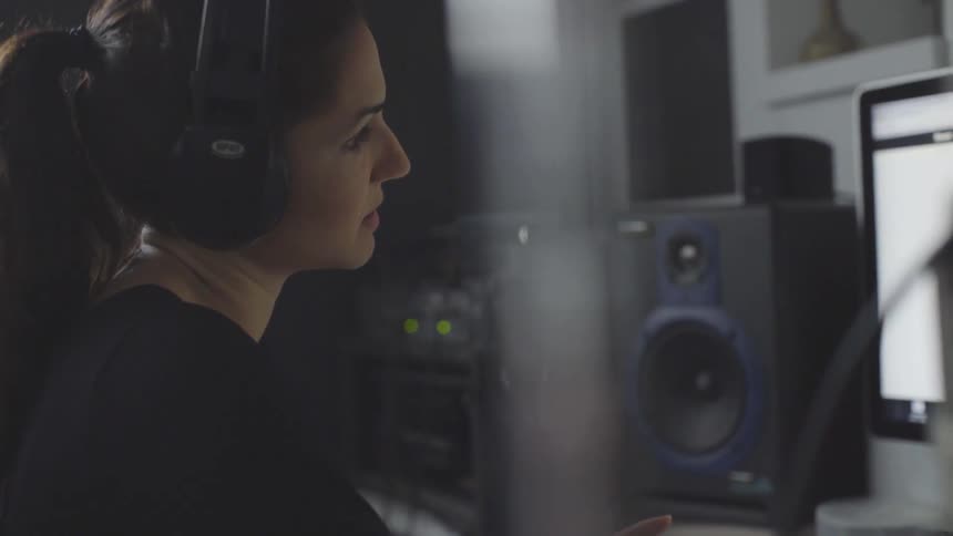 Woman wears headphones while looking at a computer monitor
