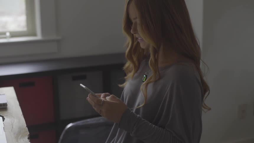 Woman sits at desk texting
