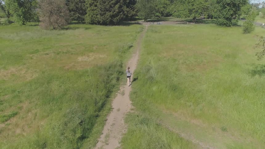 A woman runs down a path toward the trees