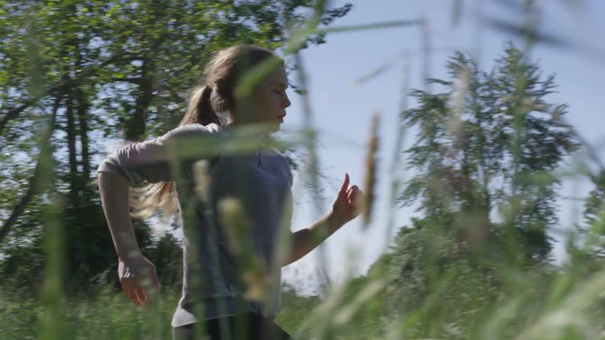 A girl runs through a field of tall grass