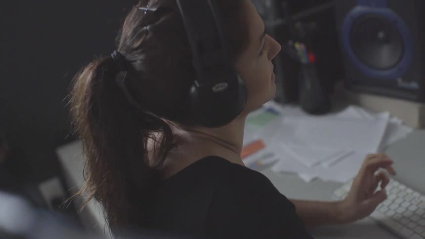 White woman typing on a keyboard while wearing a headphone
