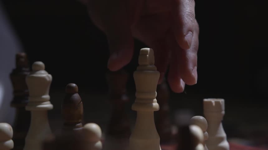 A hand places a white chess piece on a chess board