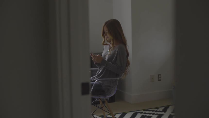 Woman sitting on a chair while typing on phone