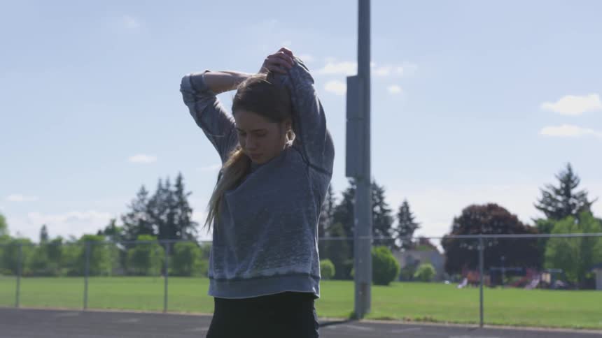 A woman warming up and stretching on a track field