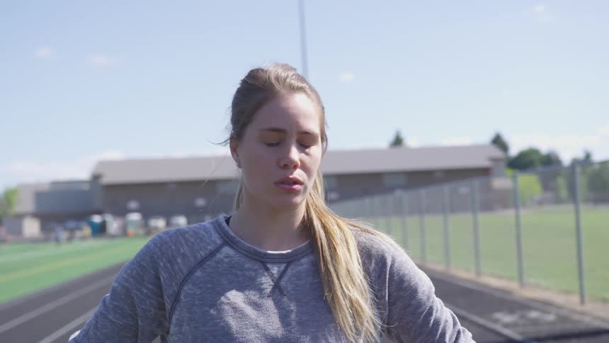 Woman stands on a track as the wind blows her hair