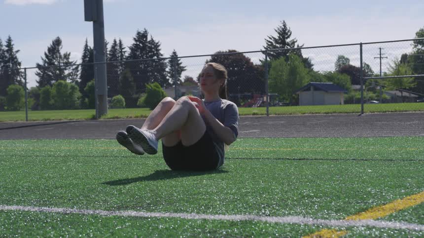 Young woman exercising in the middle of a football field