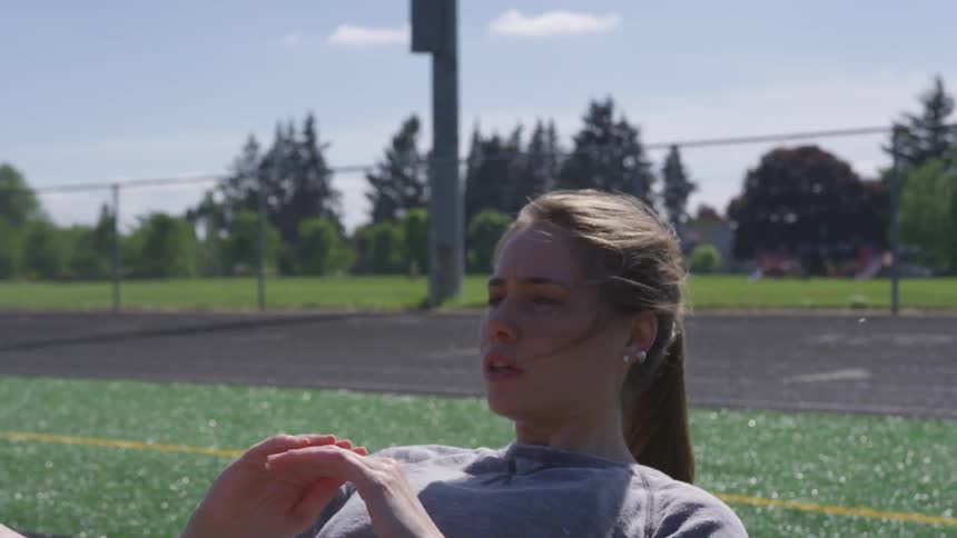 Young woman exercising at a football field