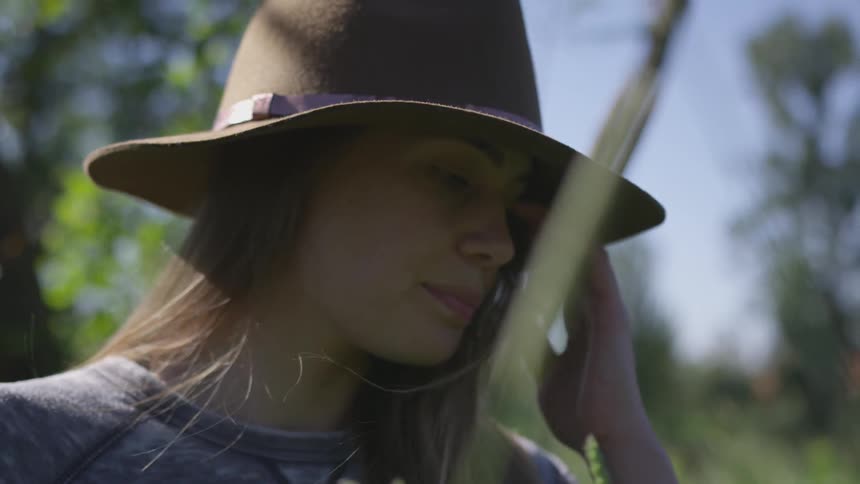 A woman with a hat outside with the wind blowing in her hair