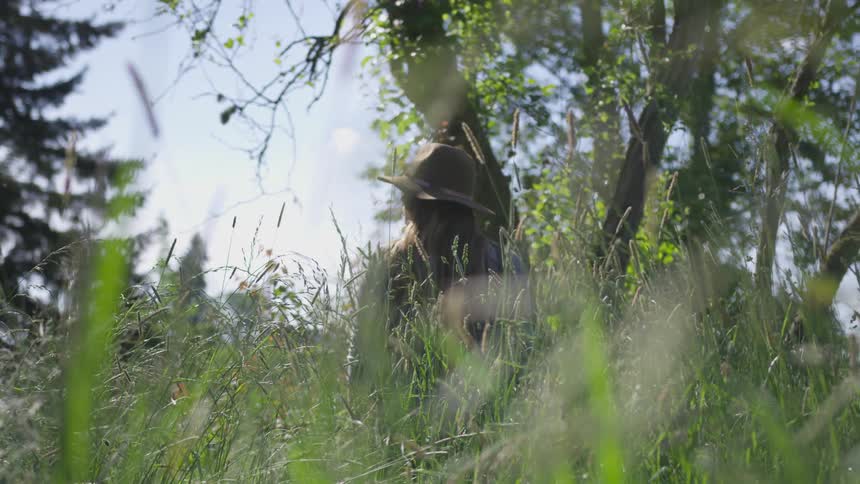 Woman with a sun hat standing on a tall grass field