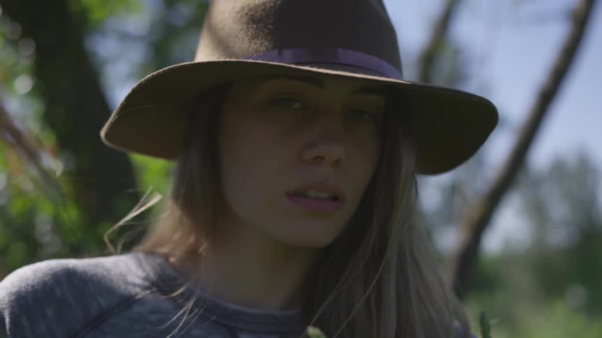 A woman wearing a hat turns her head as the wind blows her long hair