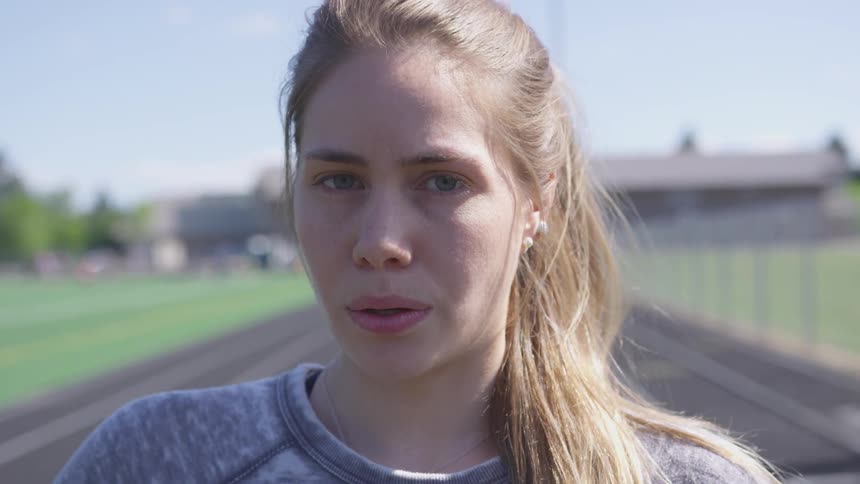 A woman takes deep breaths standing on a track