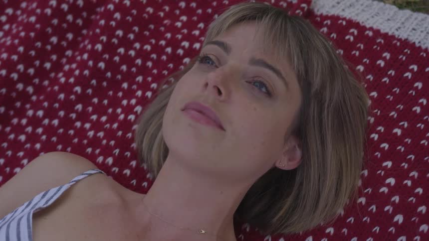 Woman lying down on patterned carpet opens her eyes and look at the sky in the daytime