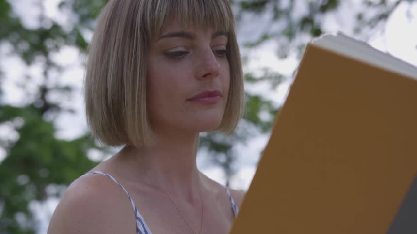 Woman reads a book outdoors