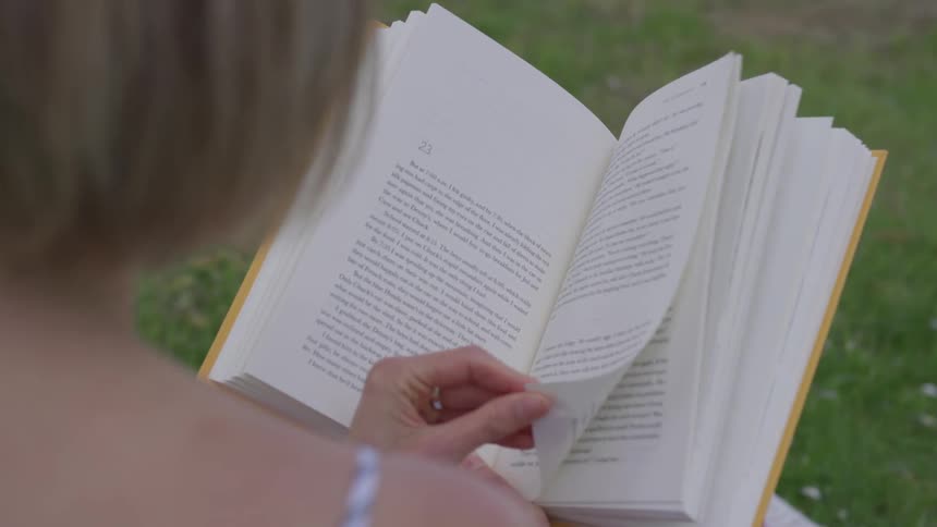 Woman reading a book sitting on the grass