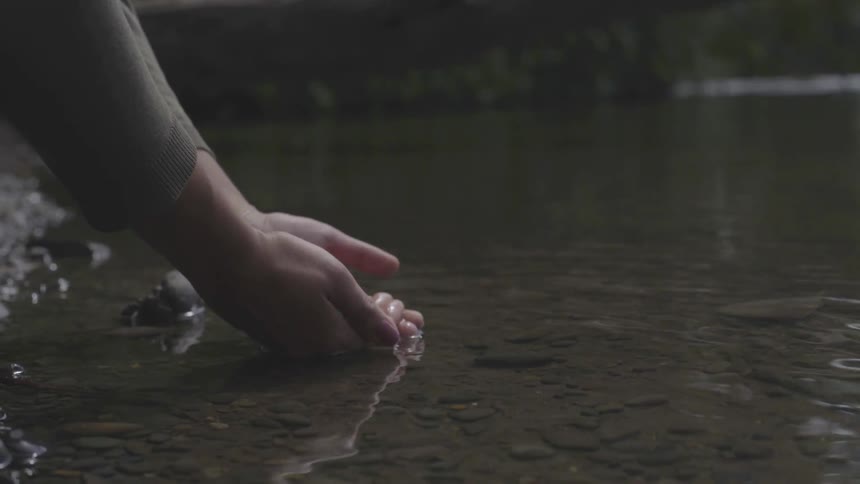 Someone dips their hands in the lake water