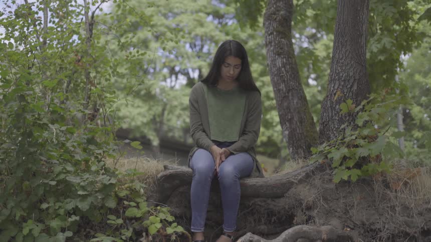 Woman sitting on the root of a tree in the forest