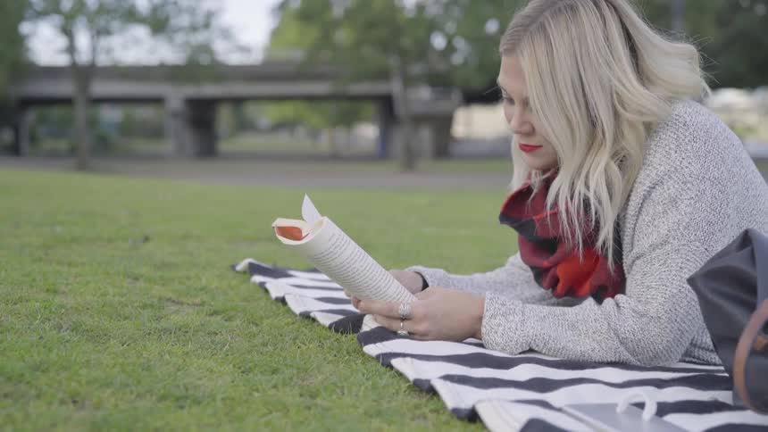 A woman is reading a book outdoors