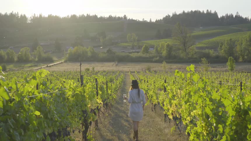 A woman with a wine glass walking through a farm