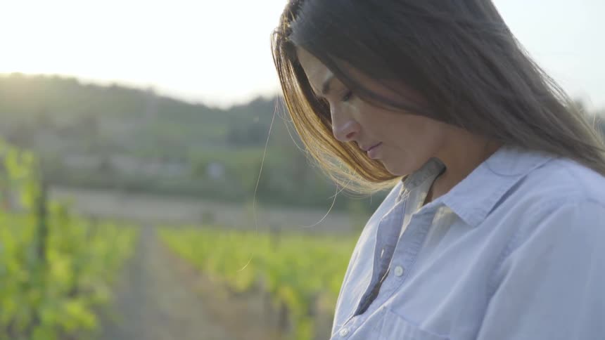 A white woman in a farm field looks up to the sky