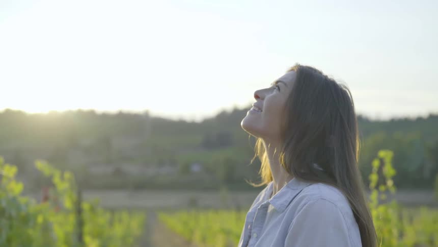 A smiling brunette white woman looks up into the sky