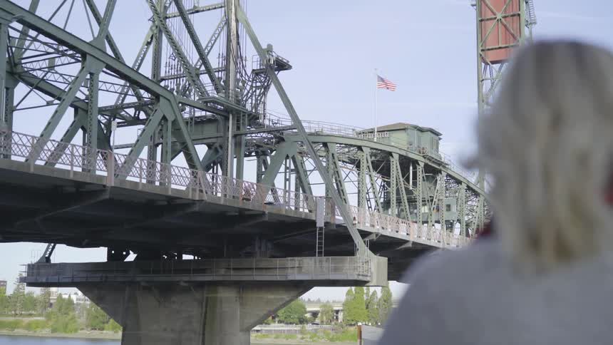 Woman stands watching bridge