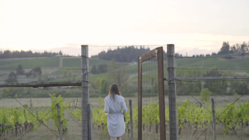 Woman opens a gate and walks into a garden
