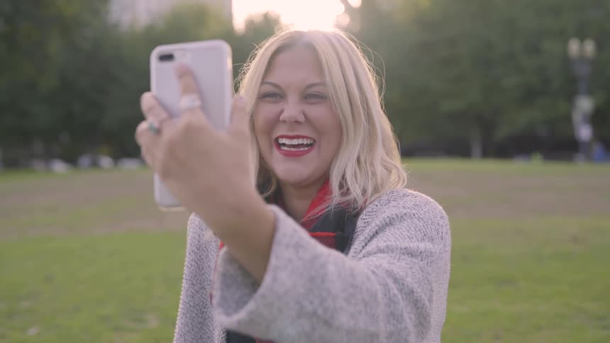 Woman stands talking via her cell phone and laughing