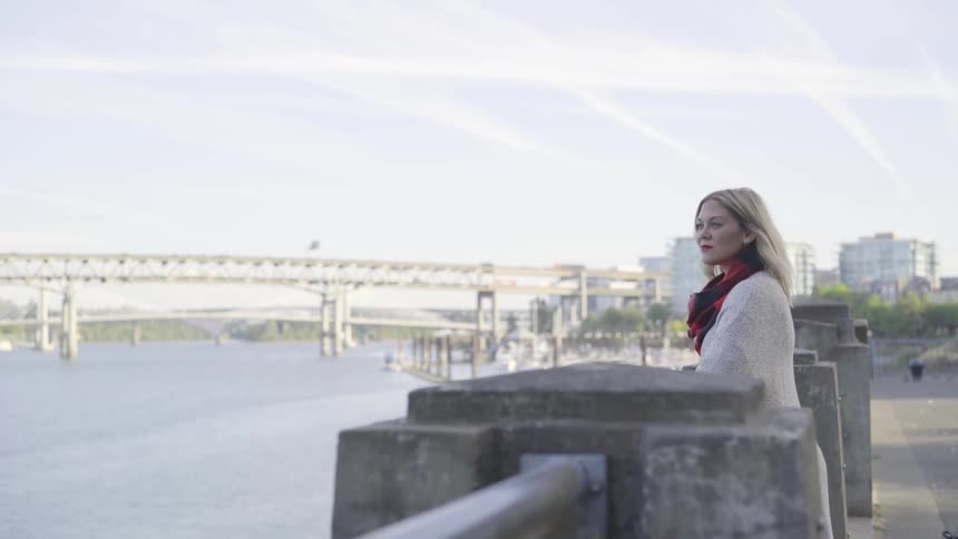 Woman stands at the waterfront and looks over the river