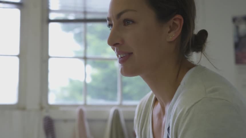 Woman uses her hands intently on something out of view