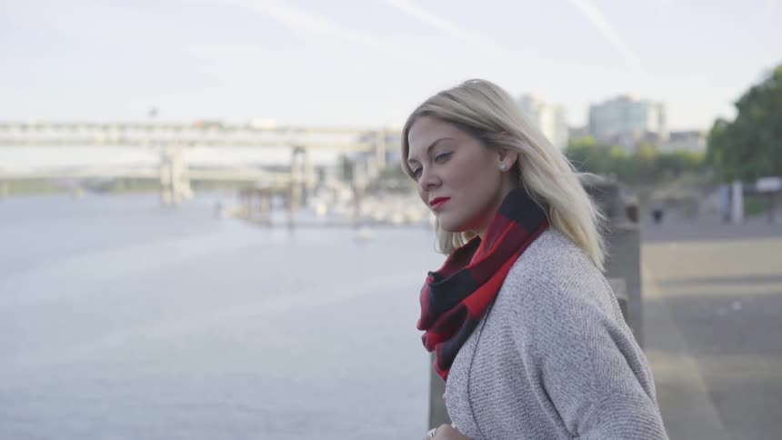A blonde woman stands at the bridge side