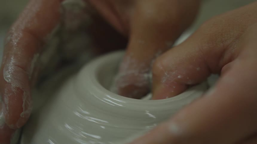 A person is making pottery with a machine