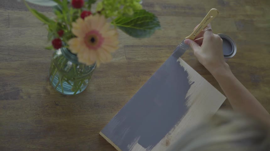 Person paints on canvas with gray paint
