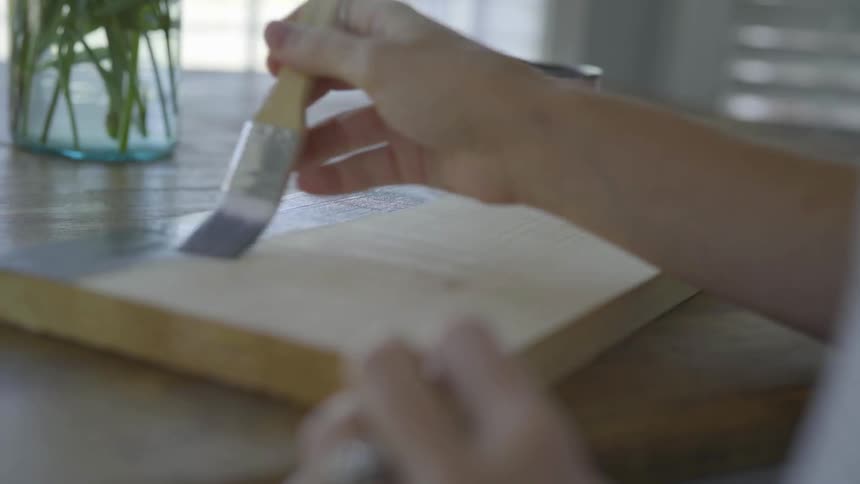 A person is painting a piece of wood