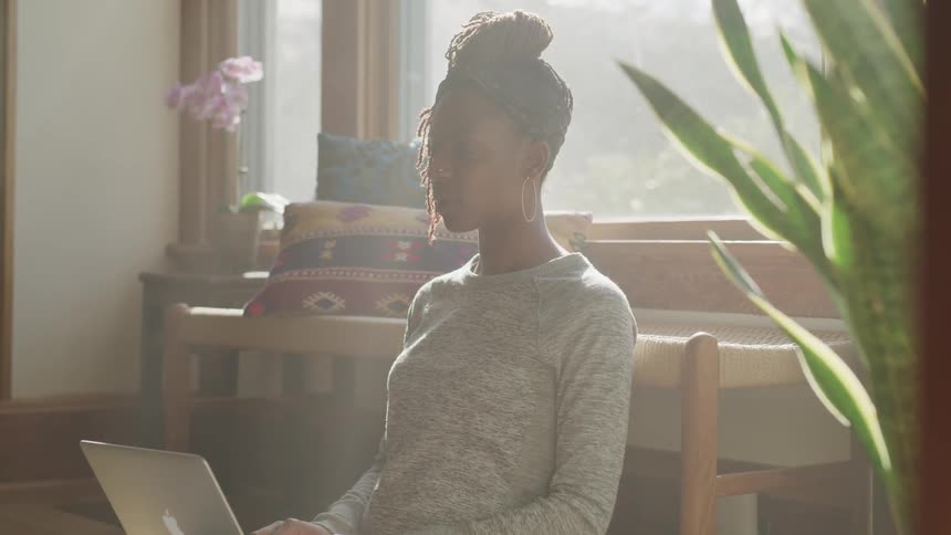 A young black woman sits with her laptop