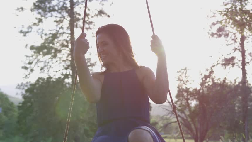 A smiling woman on a swing in the daytime